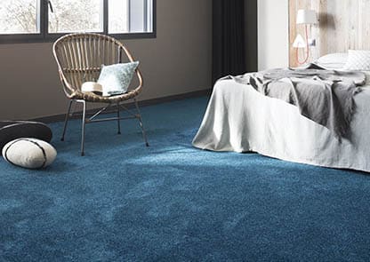 foto di una camera da letto con sul pavimento della moquette azzurra