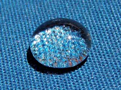 foto di una goccia non assorbita su un tessuto azzurro a cui è stato fatto il trattamento antigoccia
